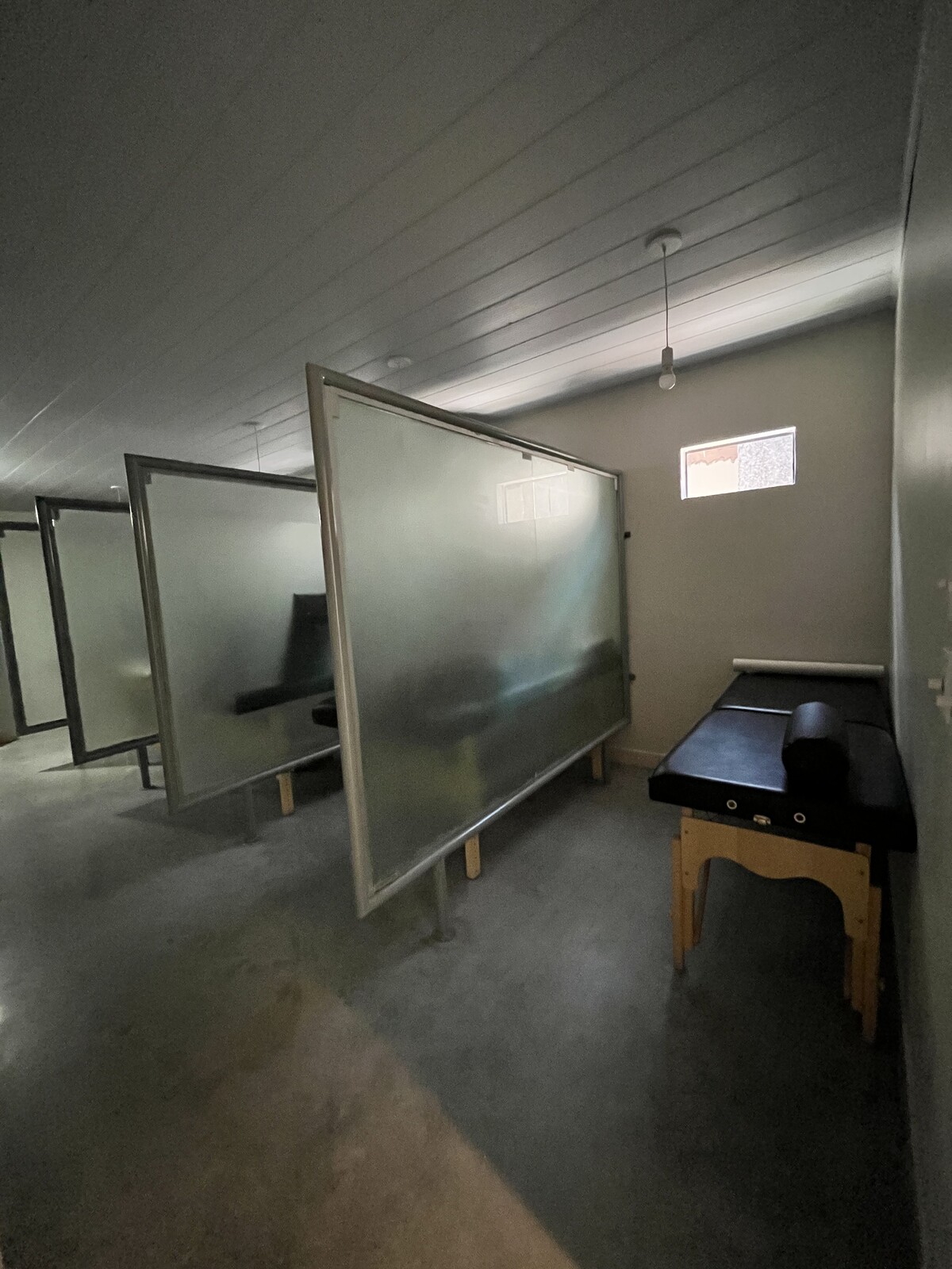 Sala de tratamento com macas separadas por divisórias de vidro