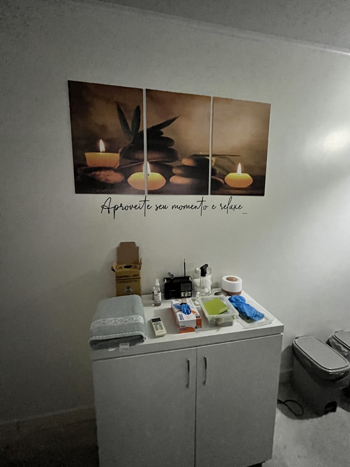 Armário com toalhas e materiais de atendimento sob quadro decorativo
