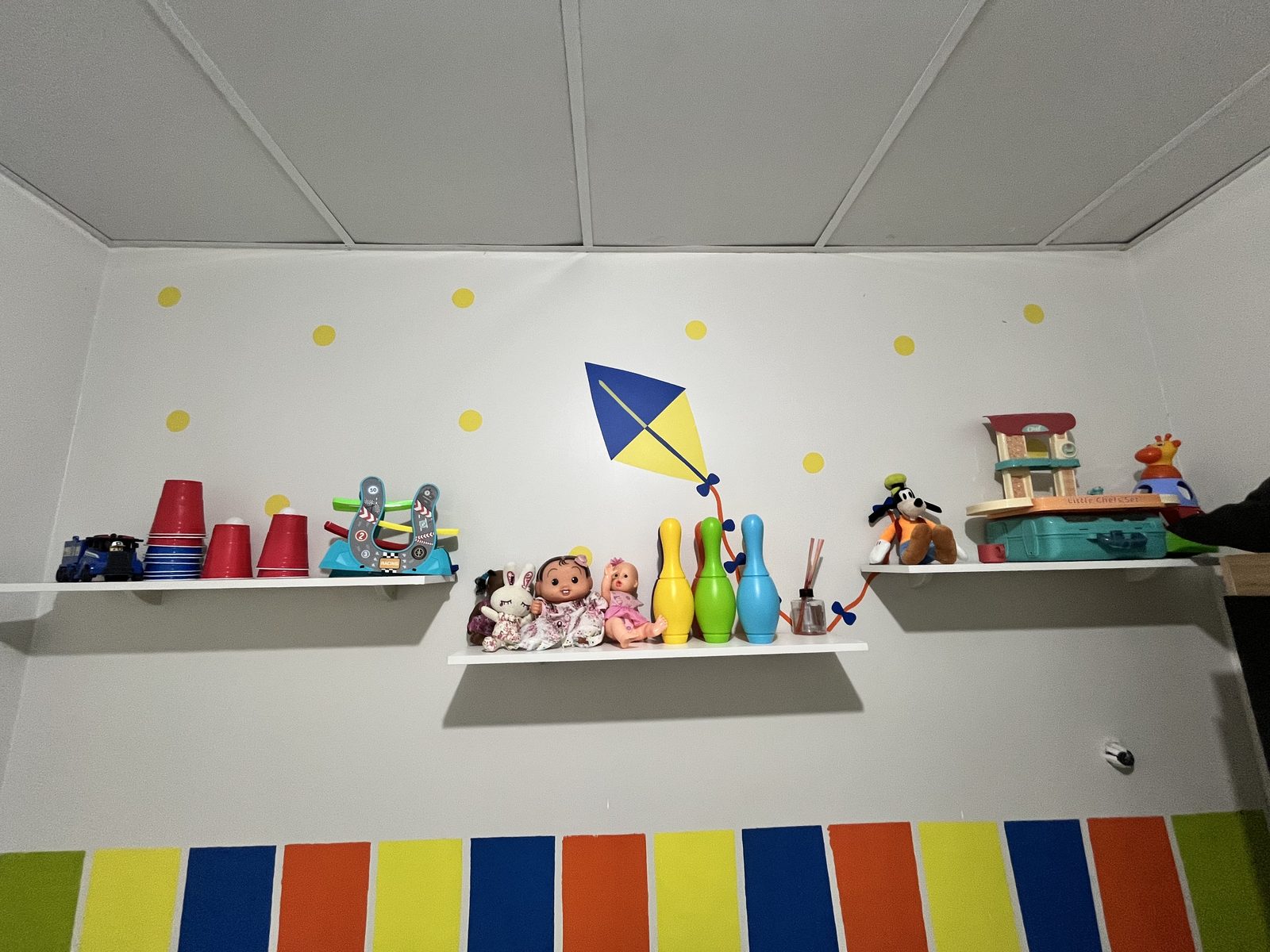 Espaço infantil com prateleiras de brinquedos e paredes coloridas