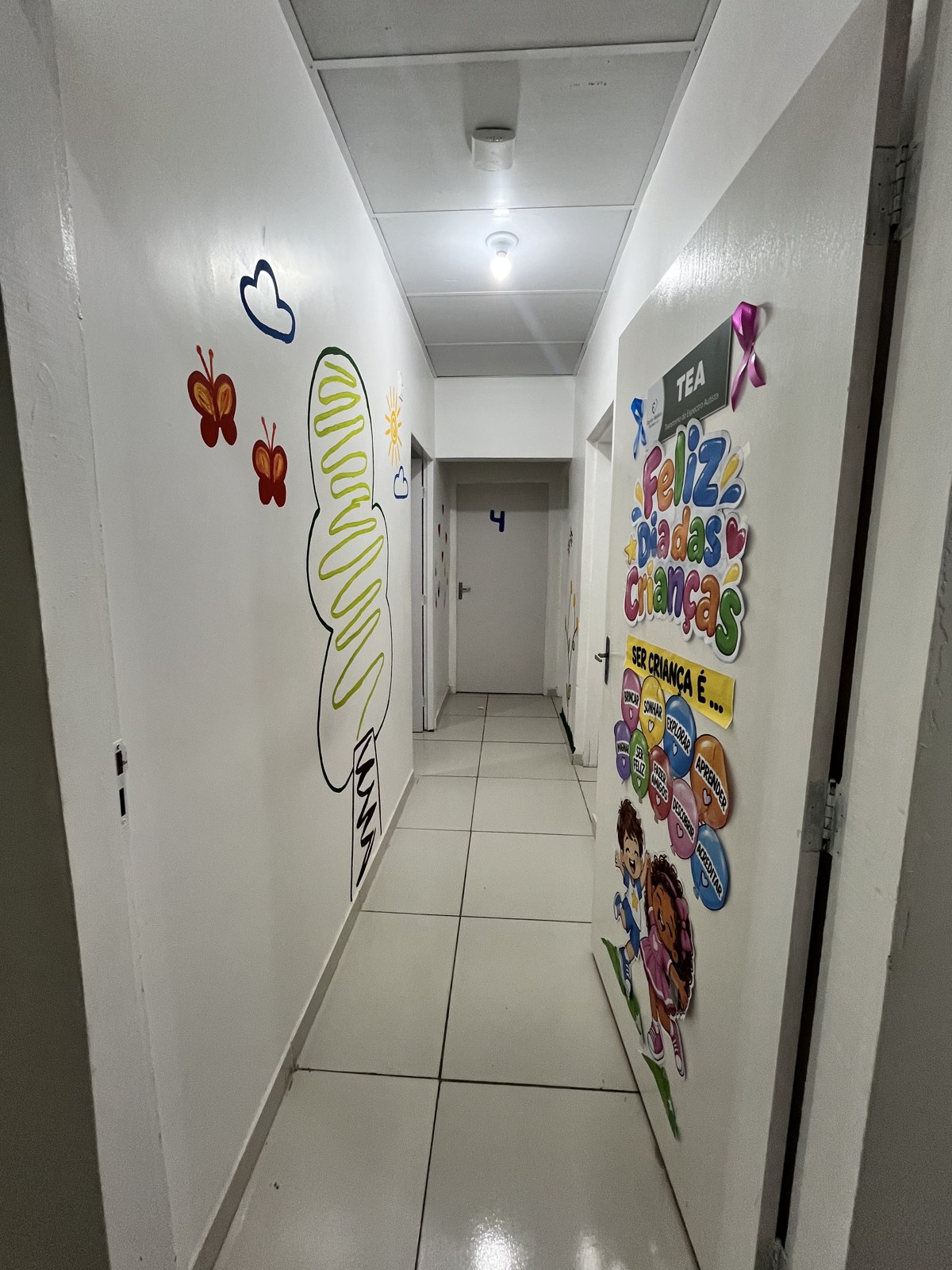 Corredor da clínica com parede decorada com pintura infantil e portas de salas