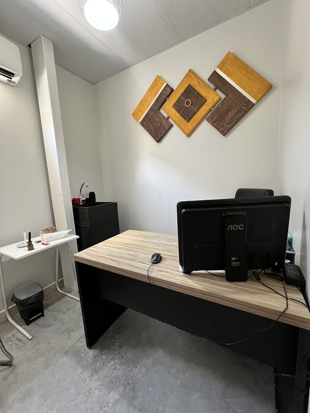 Sala de atendimento com mesa, computador e quadros decorativos na parede