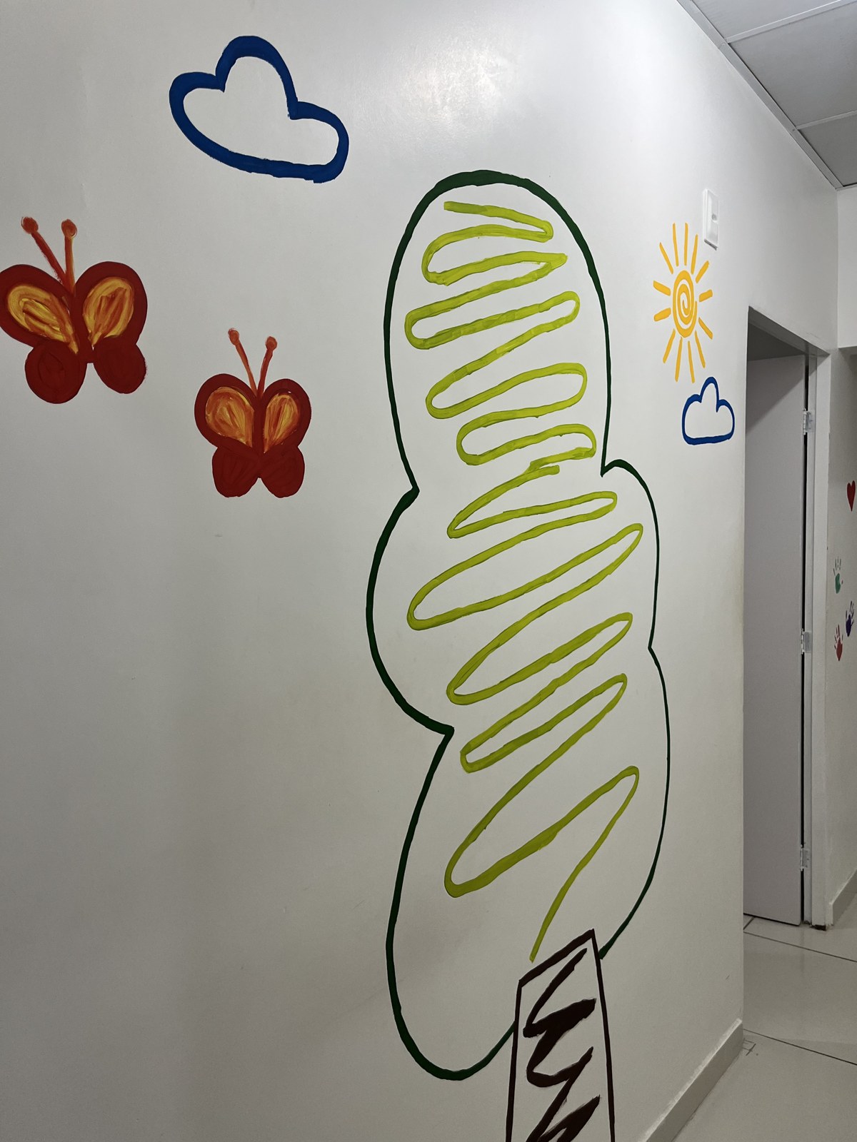 Detalhe da parede decorada com árvore, borboletas e sol